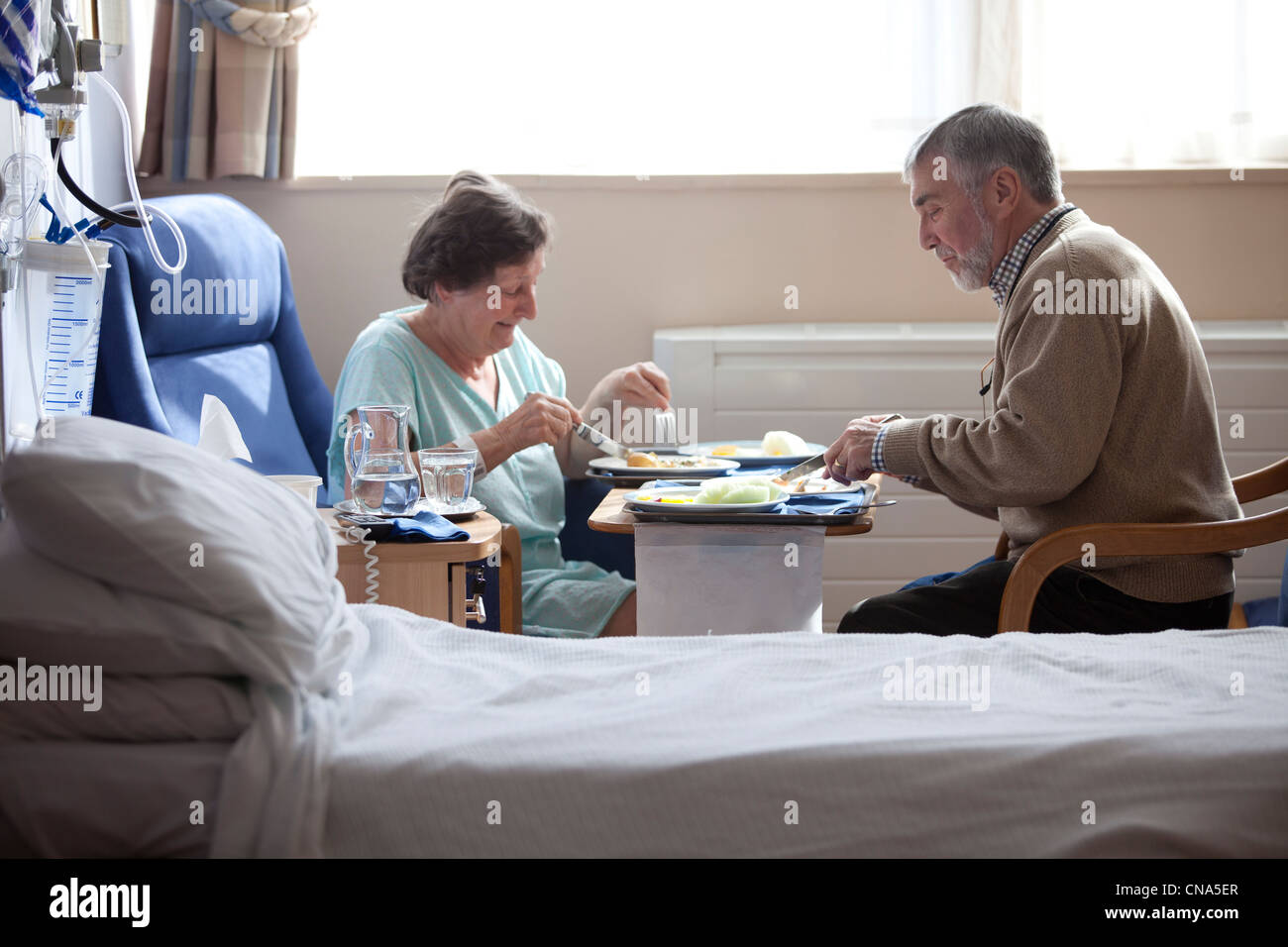 Ein älteres Ehepaar genießen Sie eine Mahlzeit in einem privaten Zimmer im Krankenhaus UK Stockfoto