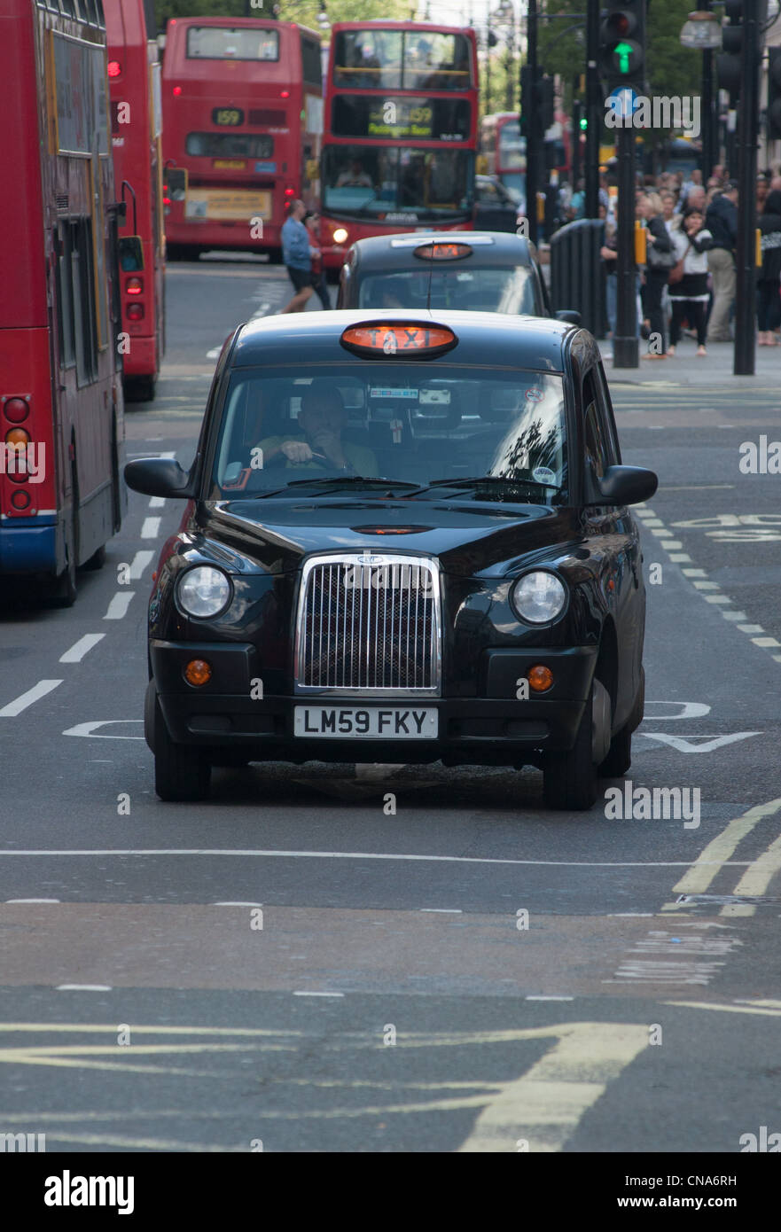 Die schwarzen Londoner Taxis bereit, mit Bussen in London, England. Stockfoto