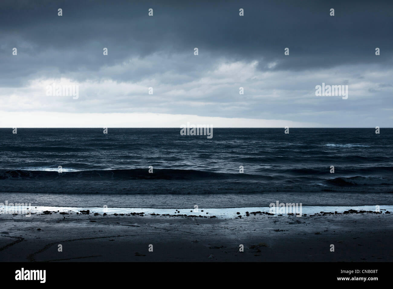 Wellen, die am Sandstrand Stockfoto