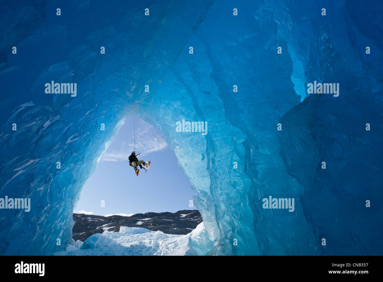 Zusammensetzung: Blick von innen eine Eishöhle eines Eisbergs als ein Eiskletterer unten Mendenhall Gletscher, Alaska Abseilung Stockfoto