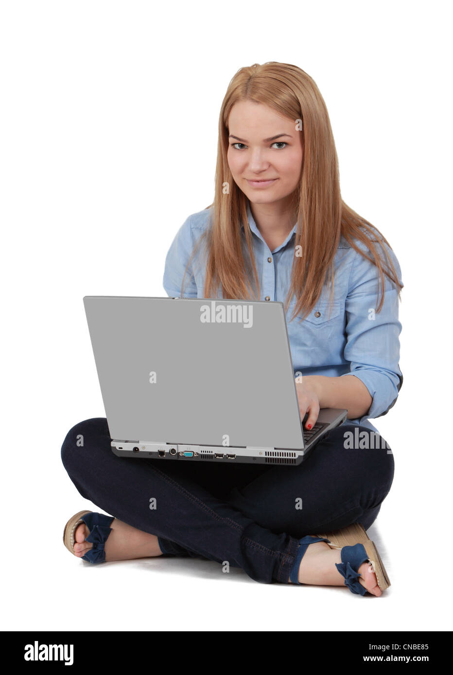 Bild einer jungen blonden Frau sitzt auf einer weißen Fläche mit einem Laptop auf dem Schoß. Stockfoto