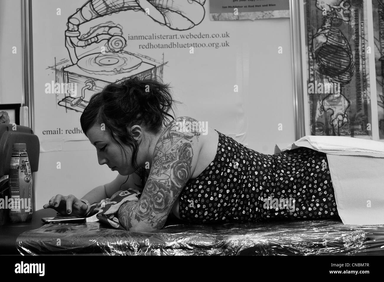 Eine Frau überprüft ihr Handy während tätowiert an das Edinburgh Tattoo Convention 2012 in Edinburgh, Schottland. Stockfoto
