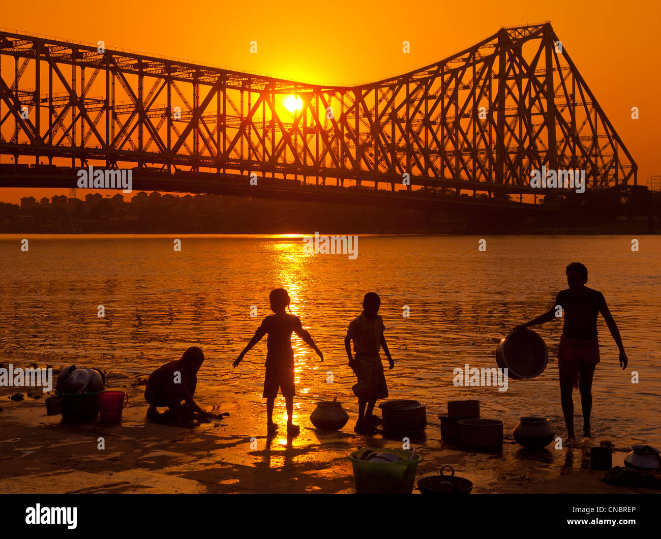 Indien, Kolkata, Westbengalen Familie Reinigung Kochutensilien im Fluss Hooghly mit Howrah Hängebrücke über Stockfoto