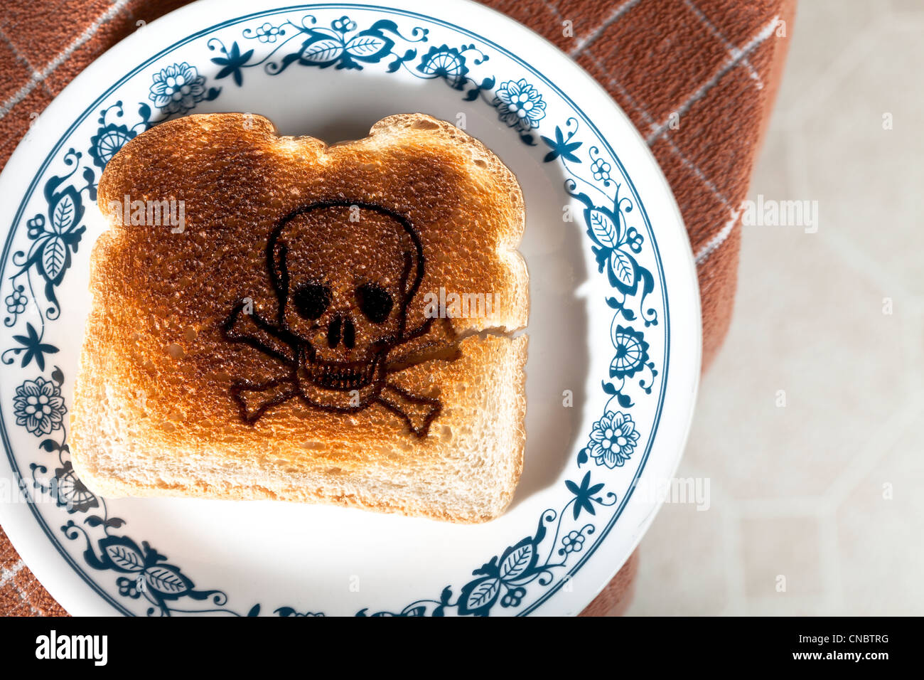 Schädel und gekreuzten Knochen verbrannt in einem Stück Toast auf einem Teller. Zöliakie Gluten-Allergie Stockfoto