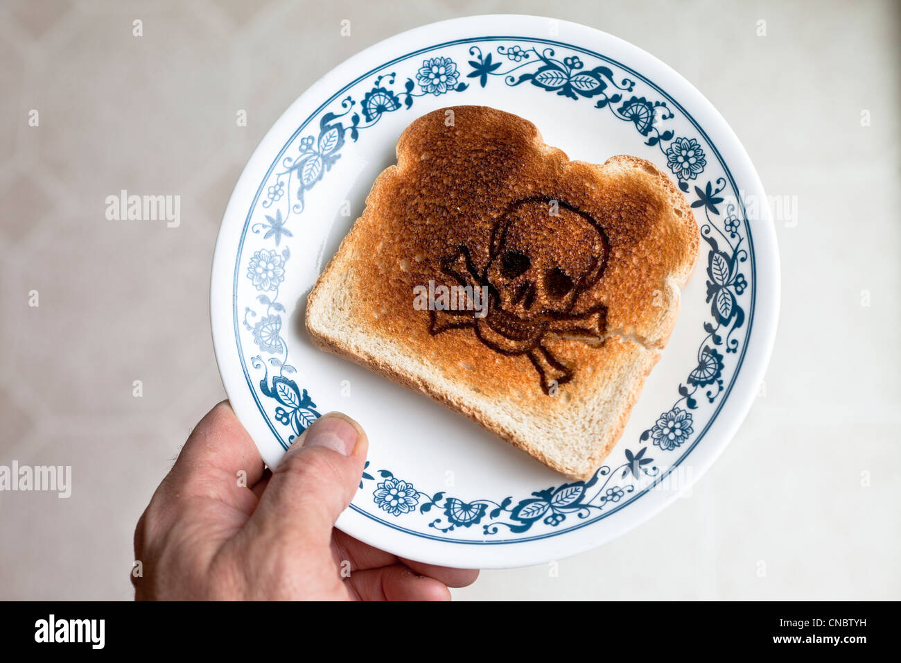 Schädel und gekreuzten Knochen verbrannt in einem Stück Toast auf einem Teller. Zöliakie Gluten-Allergie Stockfoto