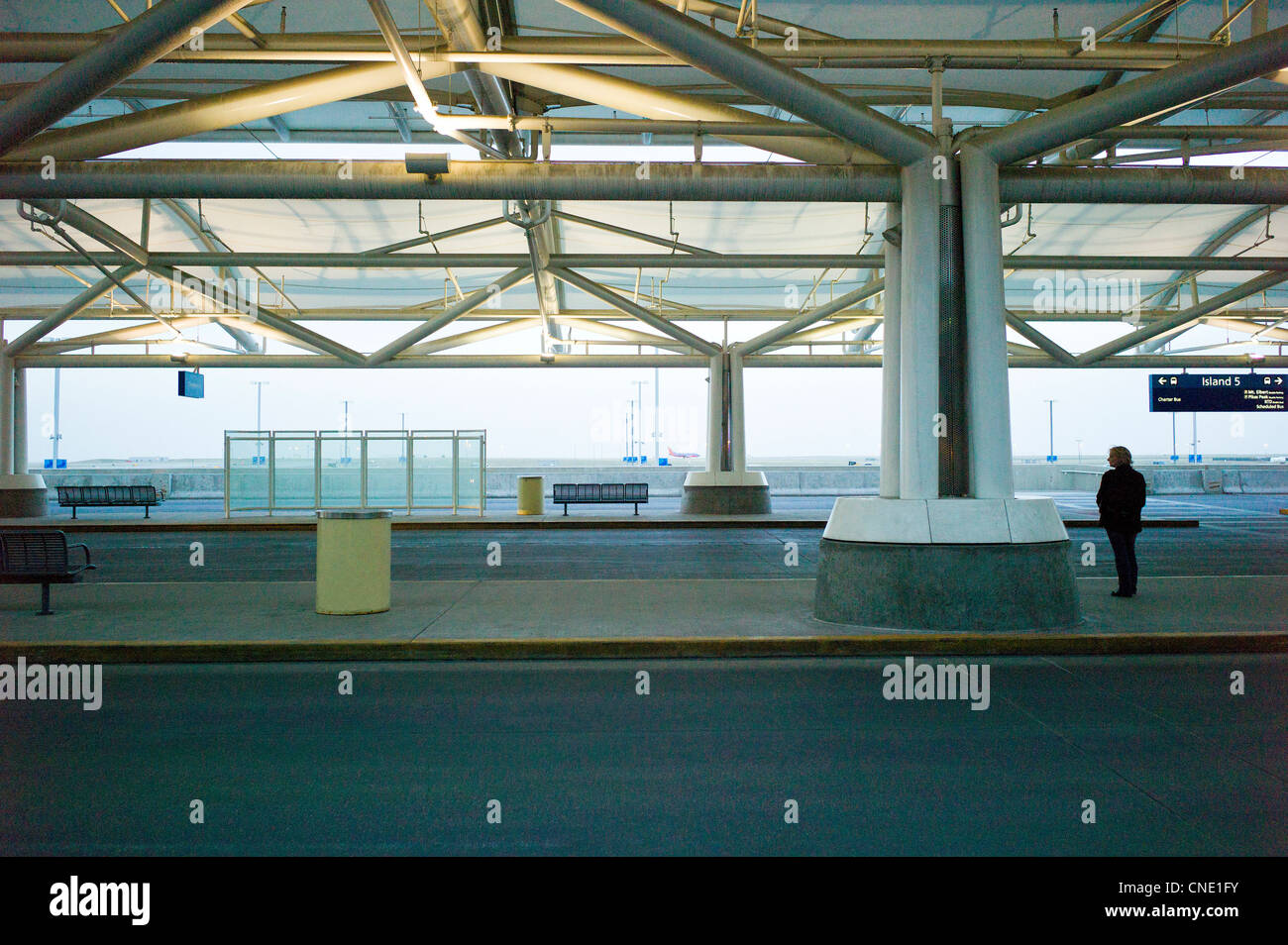 Einsame Frau wartet eine Fahrt am Terminal am Denver International Airport, Denver, Colorado, USA Stockfoto