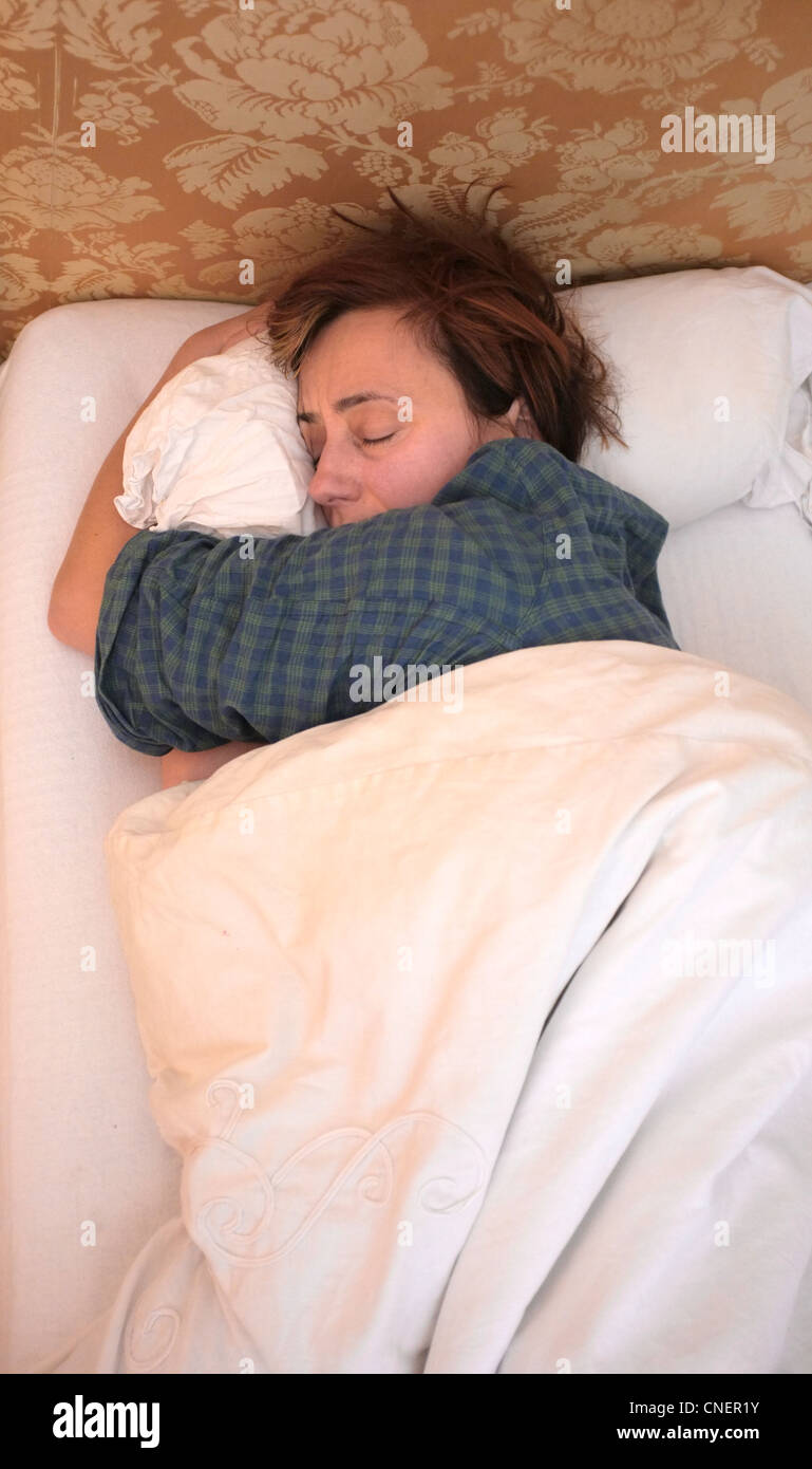 Eine erschöpfte Mutter klammert sich an ihrem letzten paar Minuten Schlaf Stockfoto