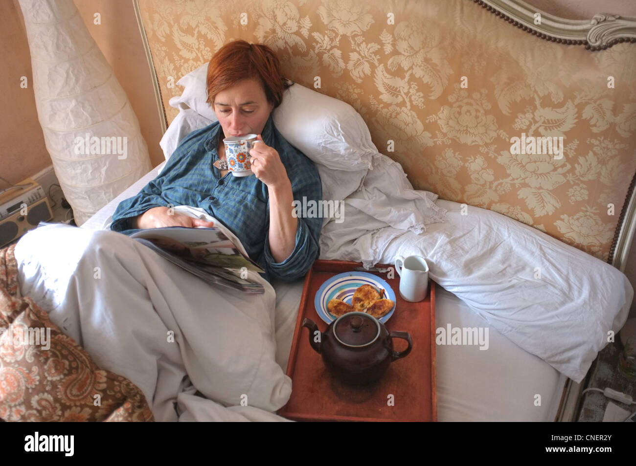 Eine Frau mittleren Alters mit Frühstück im Bett Stockfoto