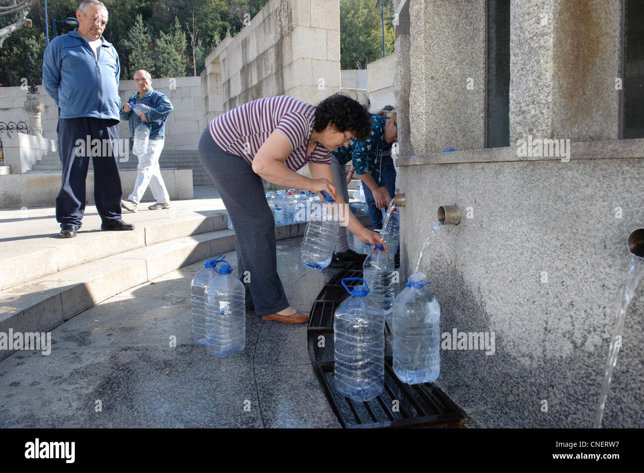 Menschen, die füllen Wasser Krüge an einen öffentlichen Brunnen in Luso, Portugal Stockfoto