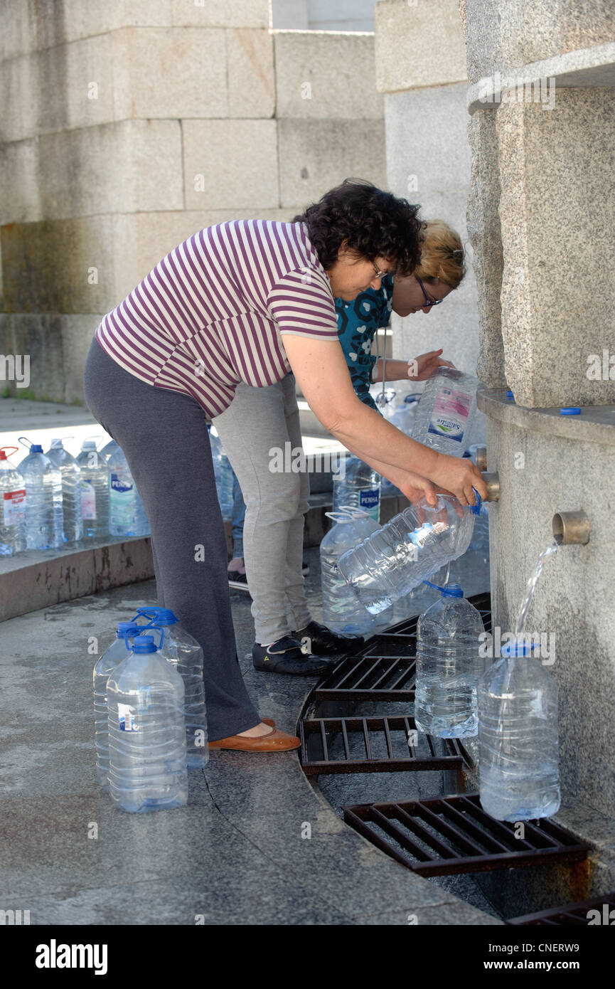 Menschen, die füllen Wasser Krüge an einen öffentlichen Brunnen in Luso, Portugal Stockfoto