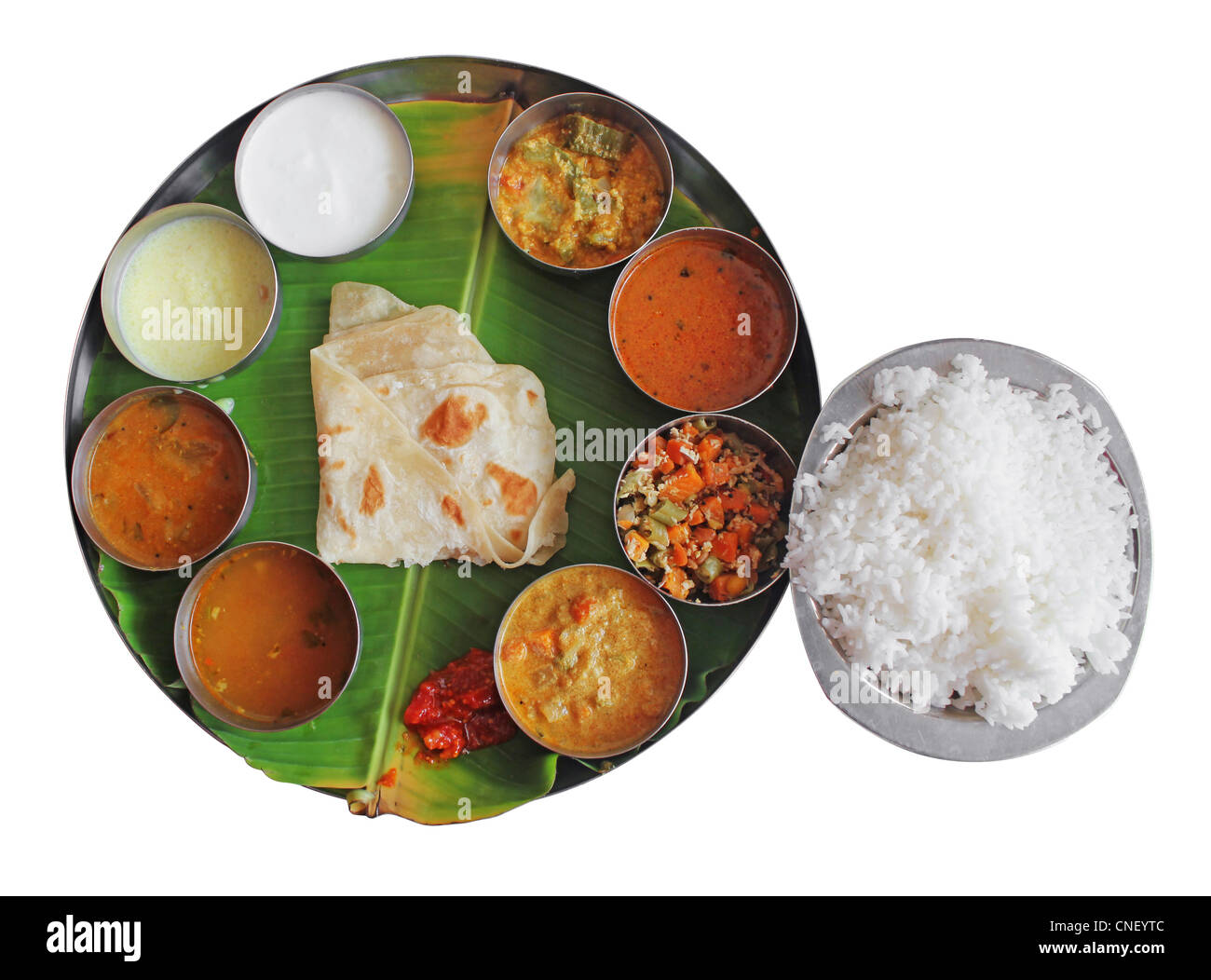 Südindische Teller Essen auf Bananenblatt isoliert auf weiss. Traditionelle vegetarische gesunde indisches Essen mit Vielzahl von Currys, Stockfoto