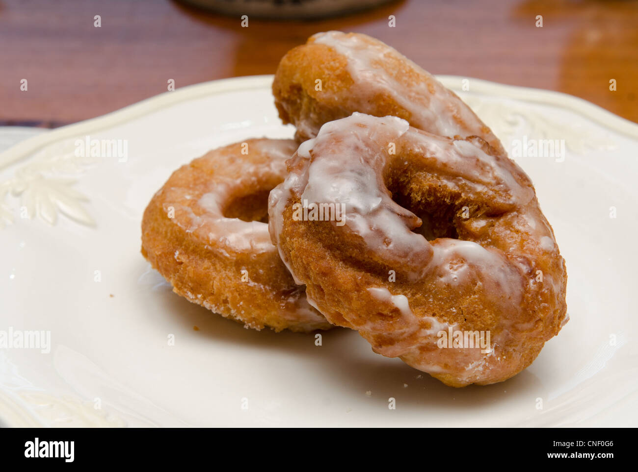 Drei hausgemachte süße glasierte Donuts, Dessert, auf einem weißen Teller. Stockfoto