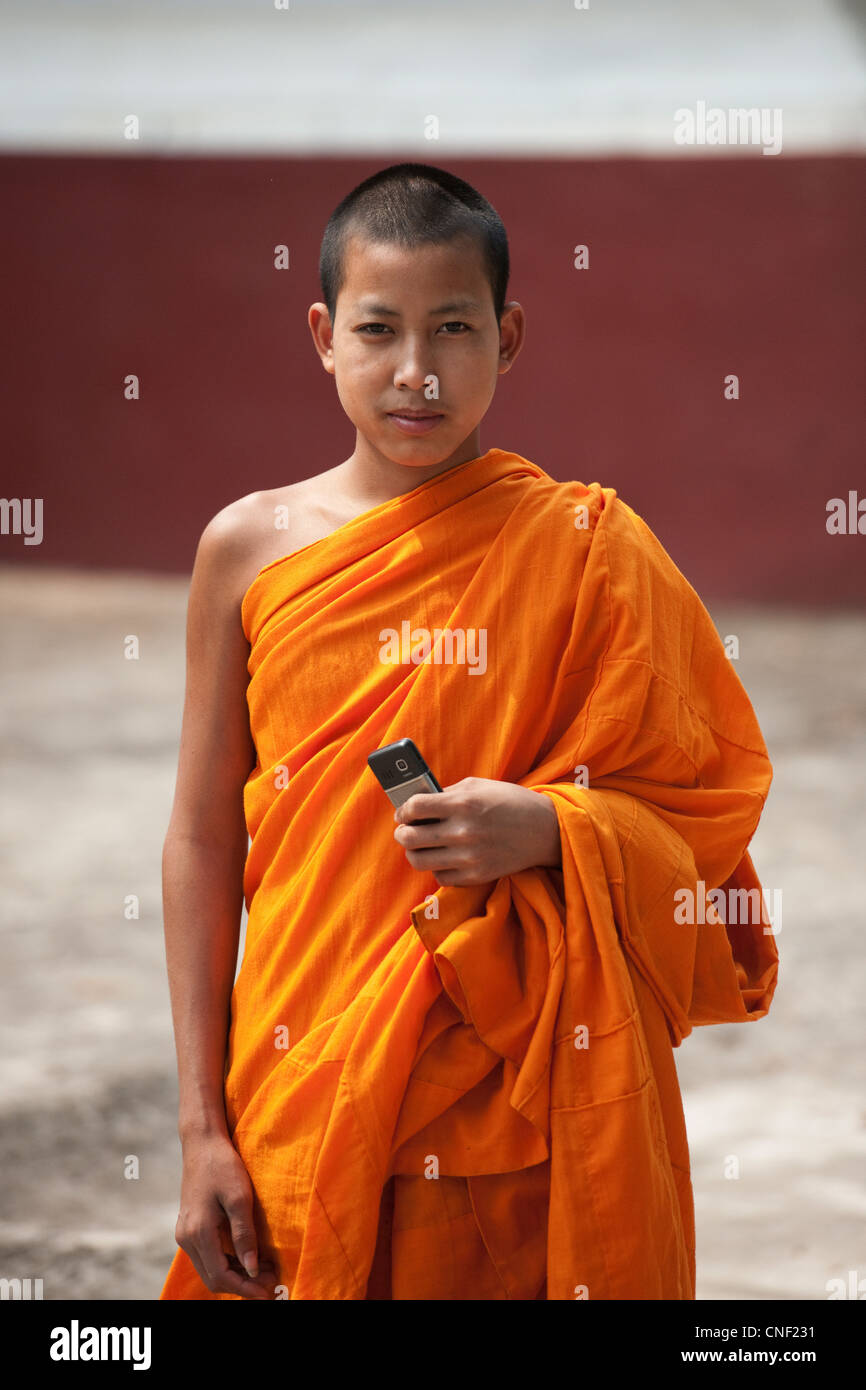 Junge Novizin Roben buddhistischer Mönch in Safran mit einem Mobiltelefon. Stockfoto