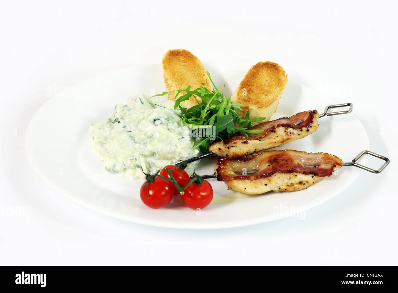 Griechische Küche - Tzatziki, Souvlaki Huhn mit Speck und Baguette auf weißem Hintergrund Stockfoto