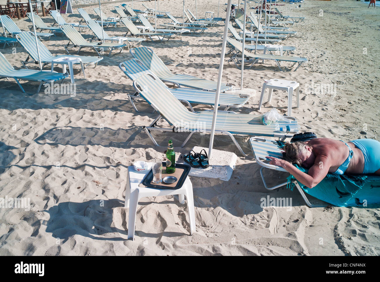 Eine Frau liegt auf einer Recling Sonnenliege am Strand in Griechenland auf der Insel Naxos. Stockfoto