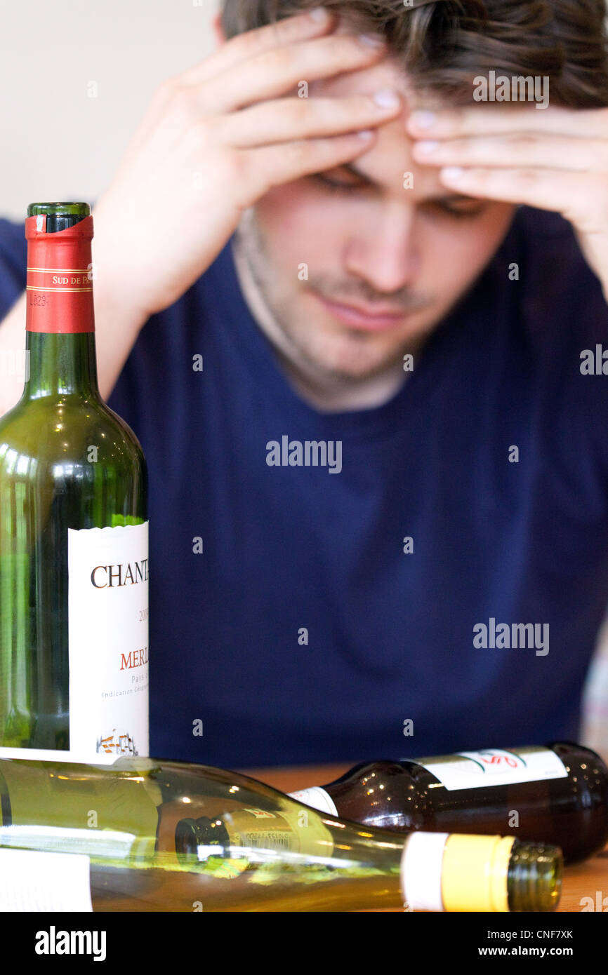 Betrunkener junge Mann mit Kater und leere Flaschen Wein und Bier, UK - gestellt durch ein Modell Stockfoto