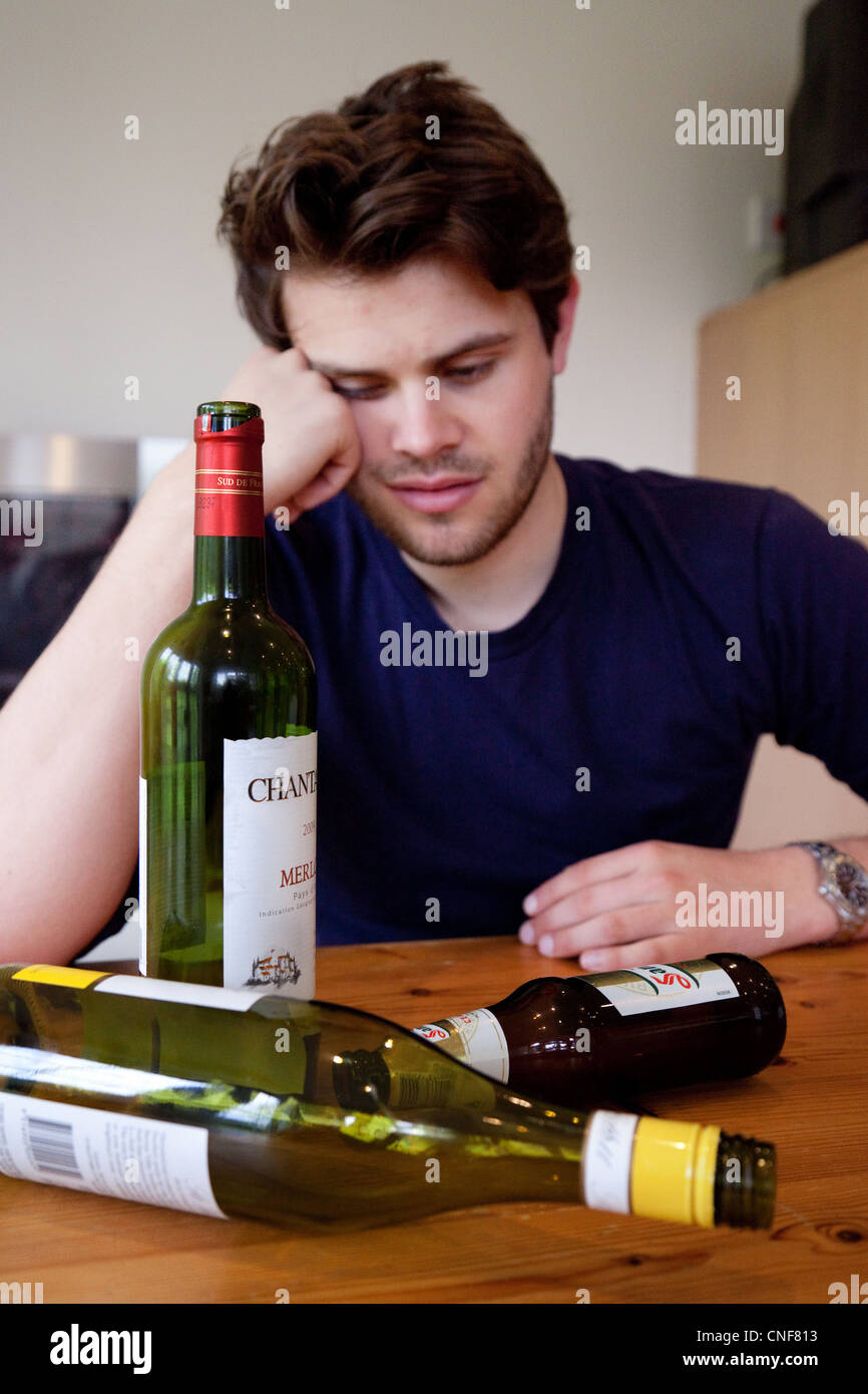 Betrunkener junge Mann mit Kater und leere Flaschen Wein und Bier, UK - gestellt durch ein Modell Stockfoto