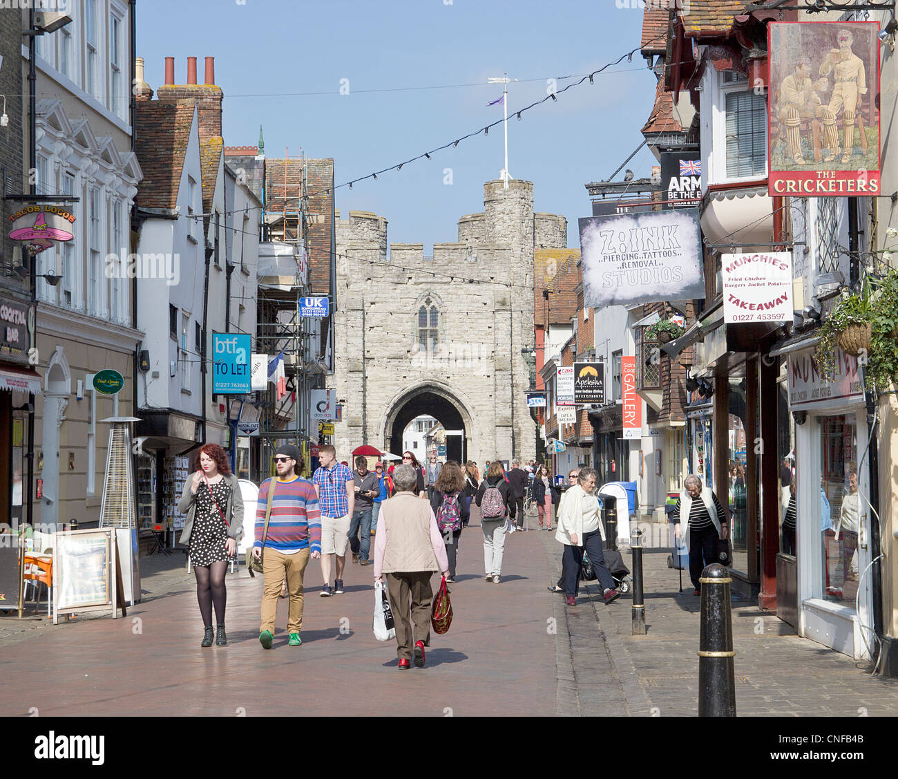 Canterbury UK High Street mit Käufern und Touristen genießen einen sonnigen Tag.  Die berühmten Westgate-Türme sind im Hintergrund. Stockfoto