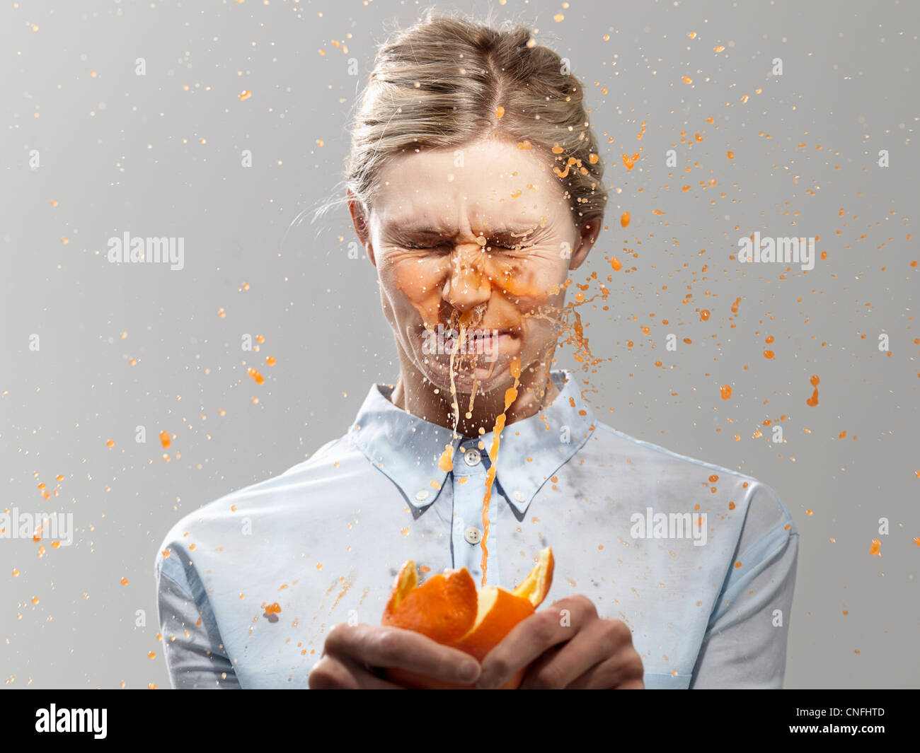 Frau spritzte mit Saft von Orange, Studio gedreht Stockfoto