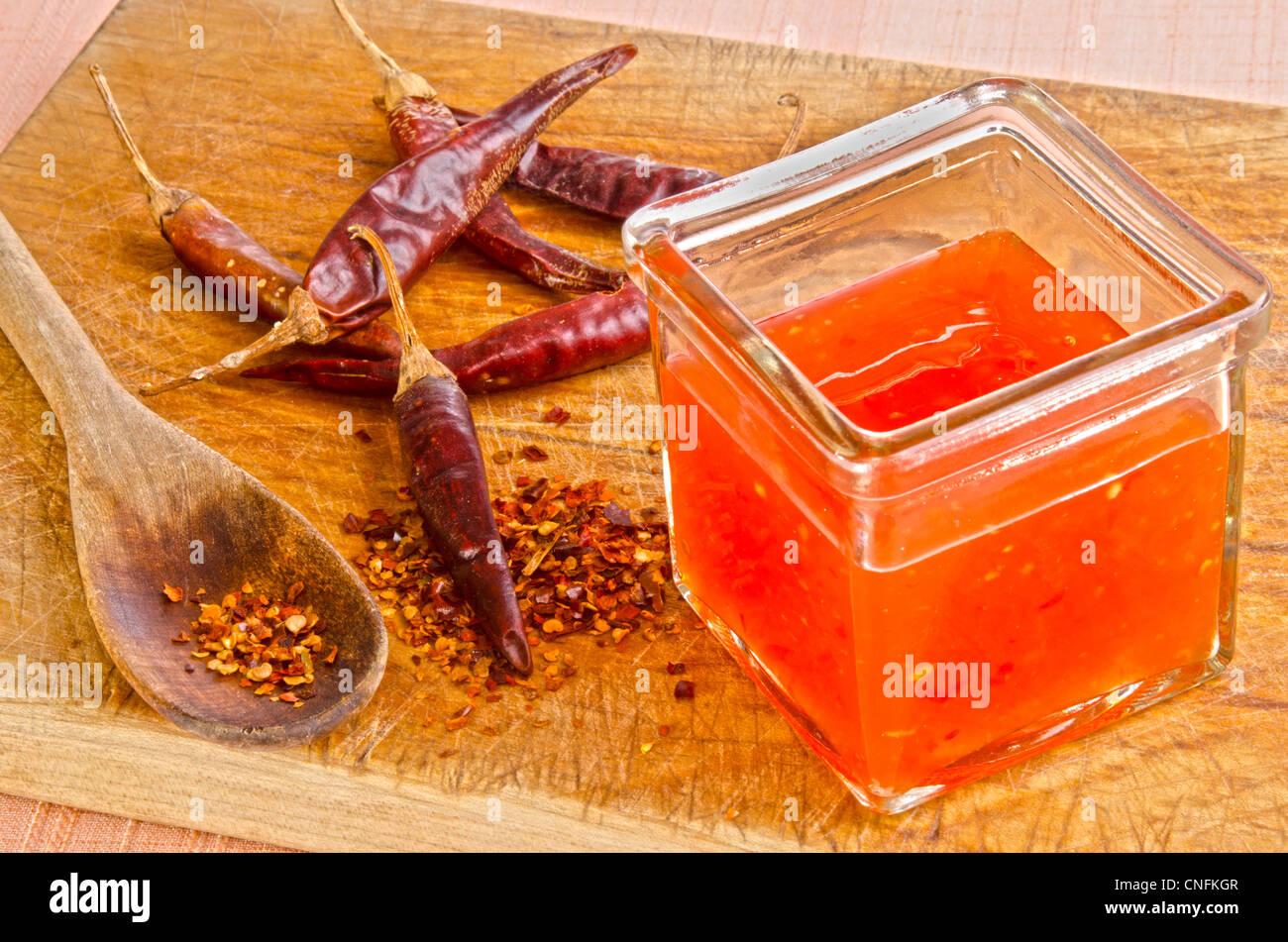 Chili-Flocken auf einen Holzlöffel und hot Chilisauce Stockfoto