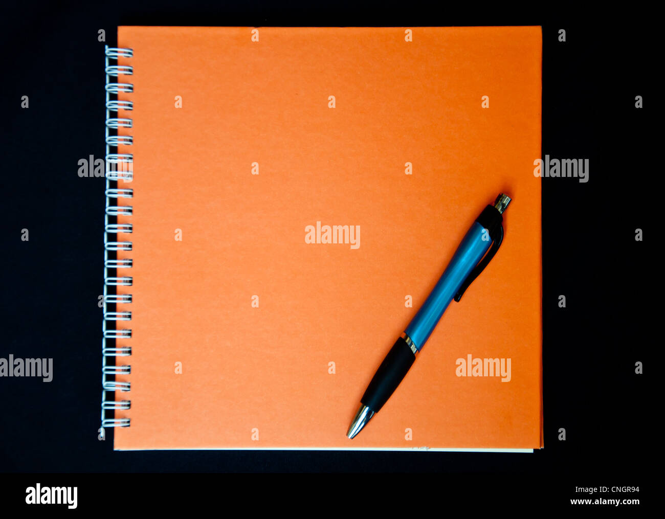 Orange Notizbuch und Stift auf schwarzem Hintergrund Stockfoto