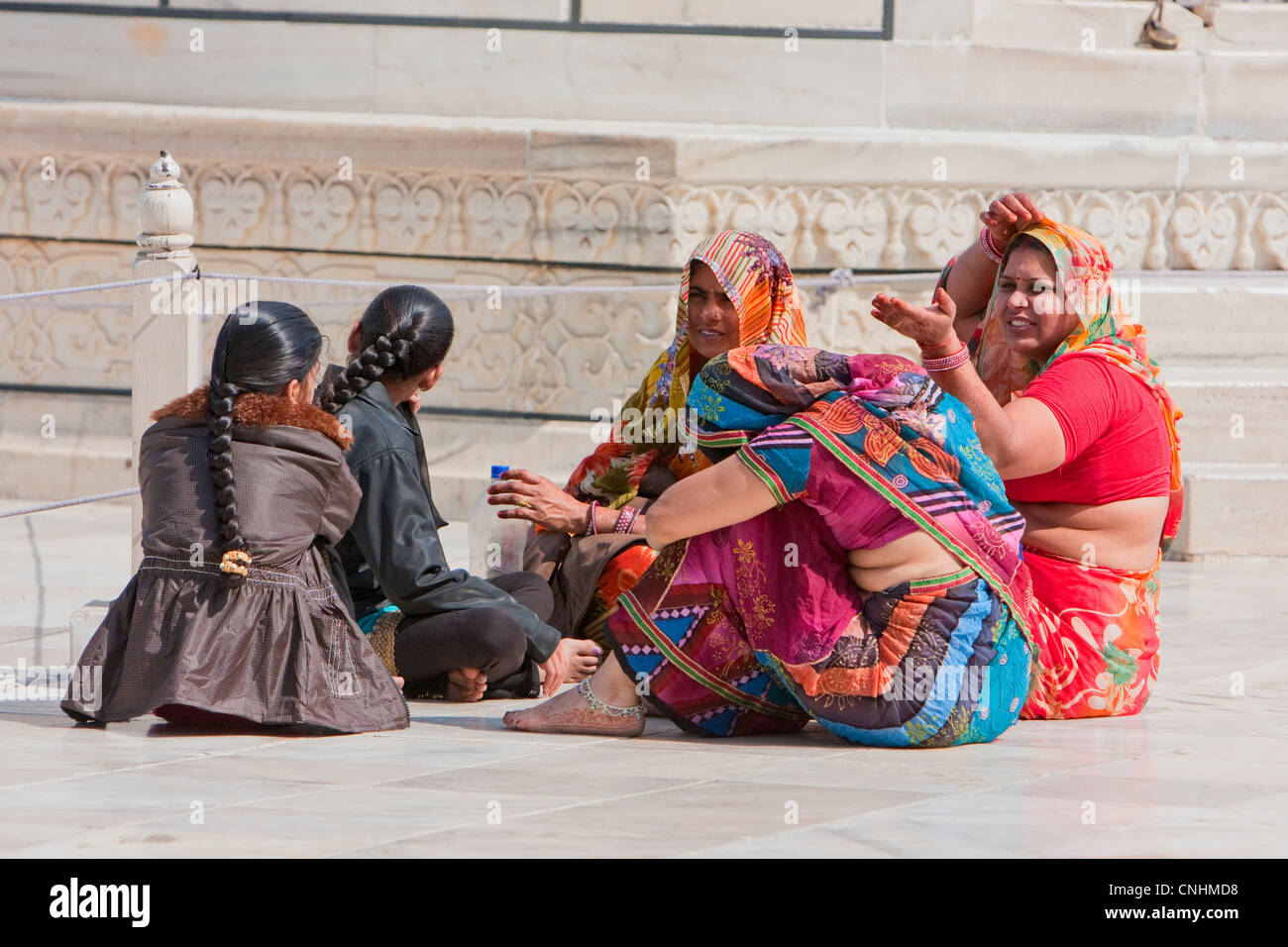 Agra, Indien. Taj Mahal. Indische Frauen tragen Saris sitzen und reden. Beachten Sie die Fußfessel. Stockfoto