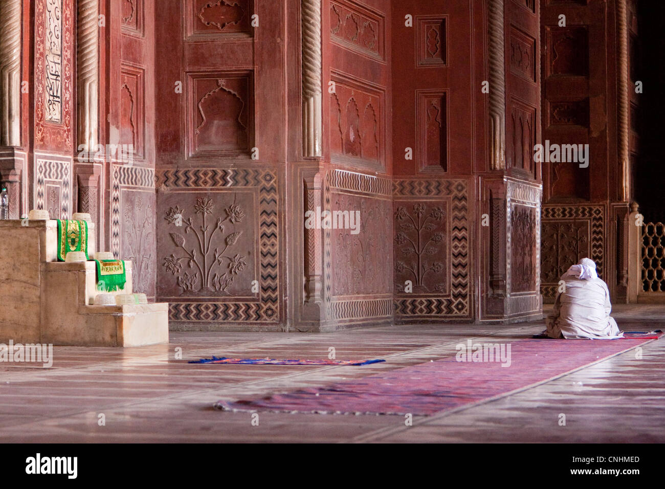Agra, Indien. Taj Mahal Moschee Innenraum. Imam lesen den Koran in Erwartung der Gebetszeit. Minibar auf der linken Seite, von der aus der Imam gibt seine Predigt. Stockfoto