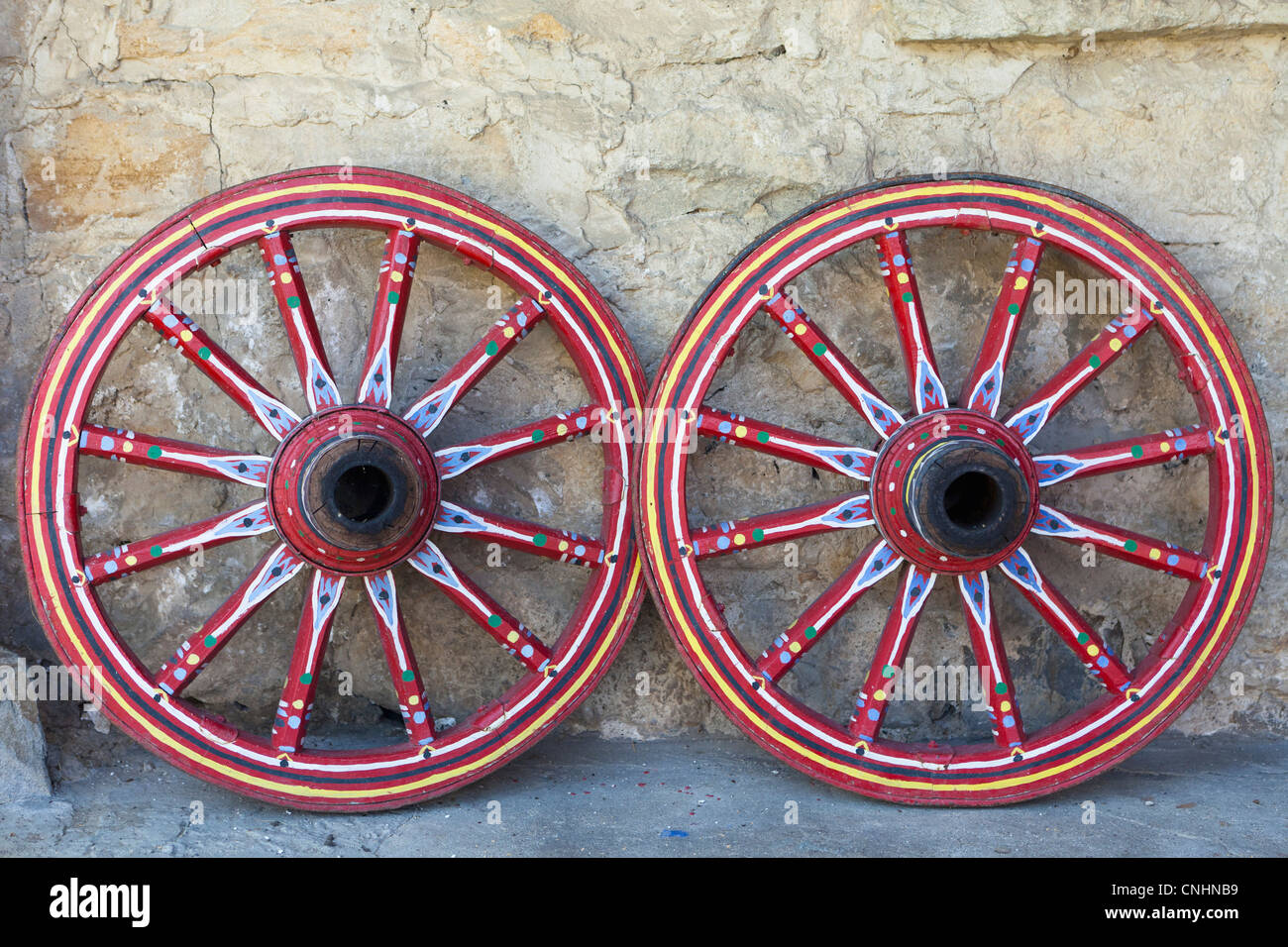 Zwei dekorativ bemalten Wagenräder an eine Wand gelehnt Stockfoto