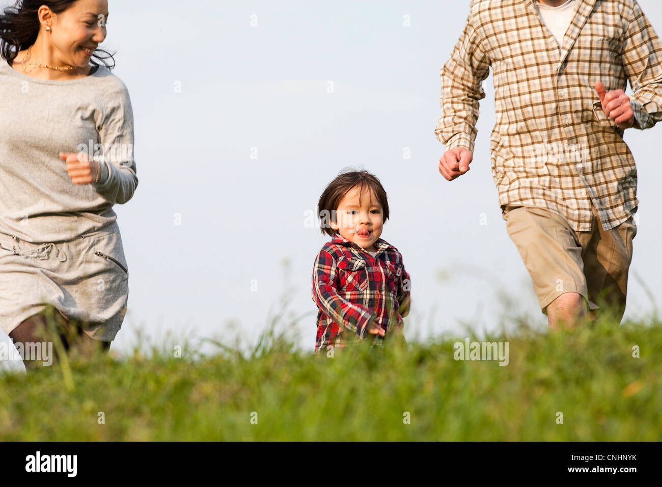Ein kleiner Junge läuft im Park zwischen seiner Mutter und Vater Stockfoto