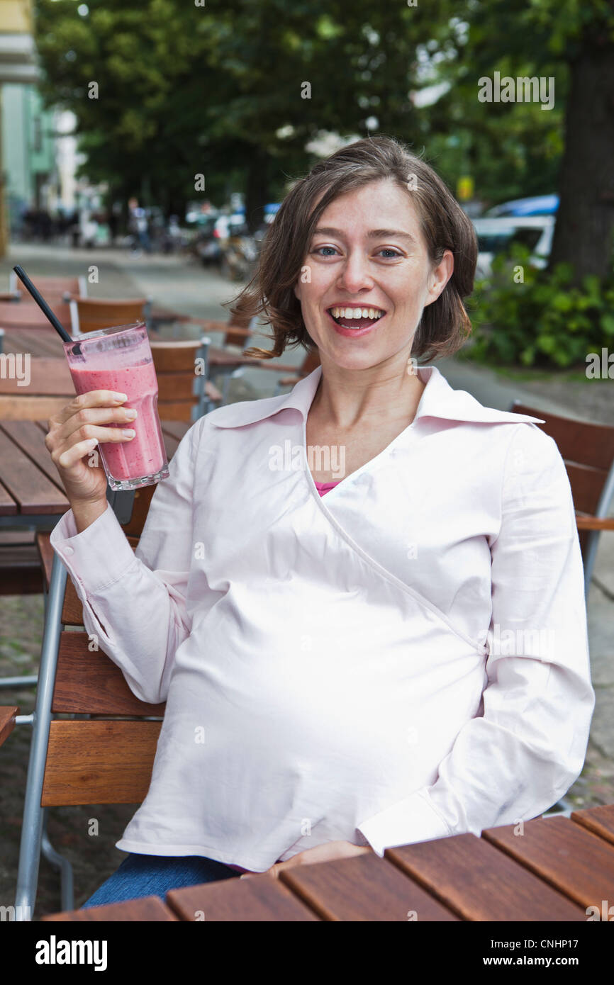 Eine schwangere Frau sitzen in einem Café hält einen Frucht-smoothie Stockfoto