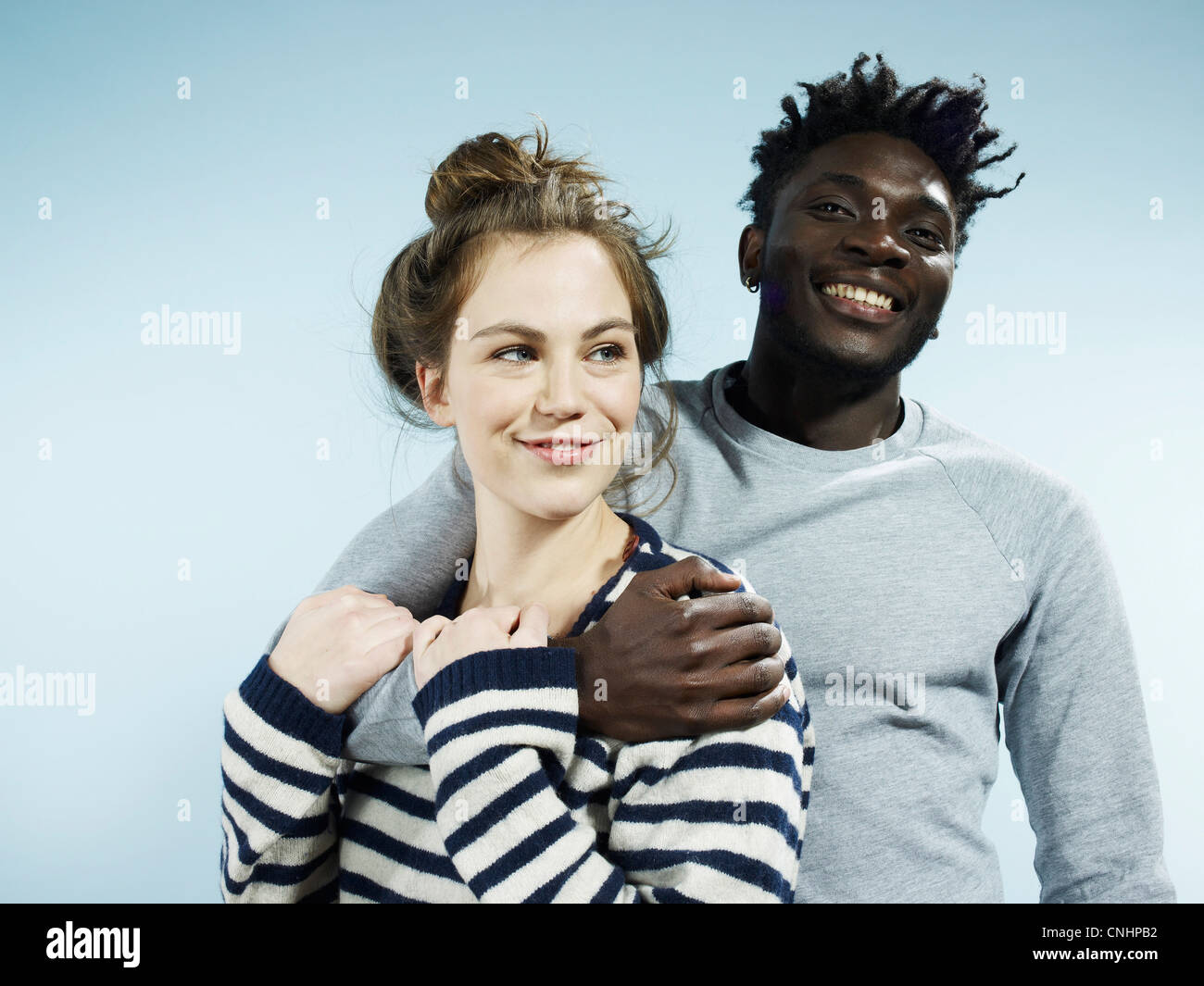 Ein lächelnder junge Mann umarmt seine lächelnde Freundin von hinten Stockfoto