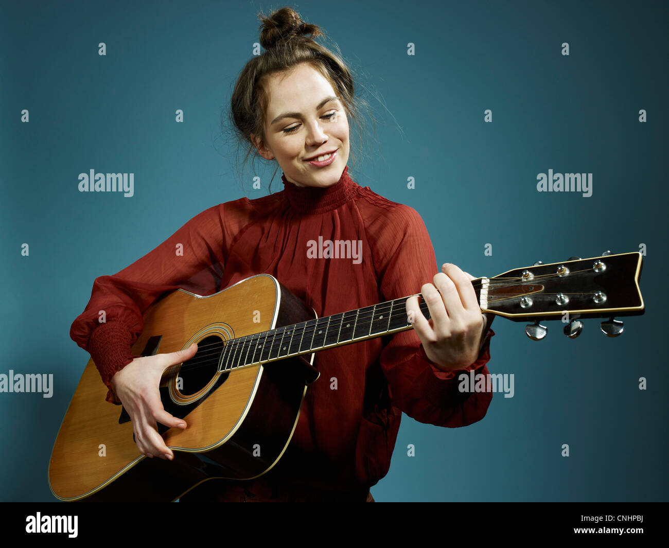 Eine junge Frau, die eine akustische Gitarre zu spielen Stockfoto