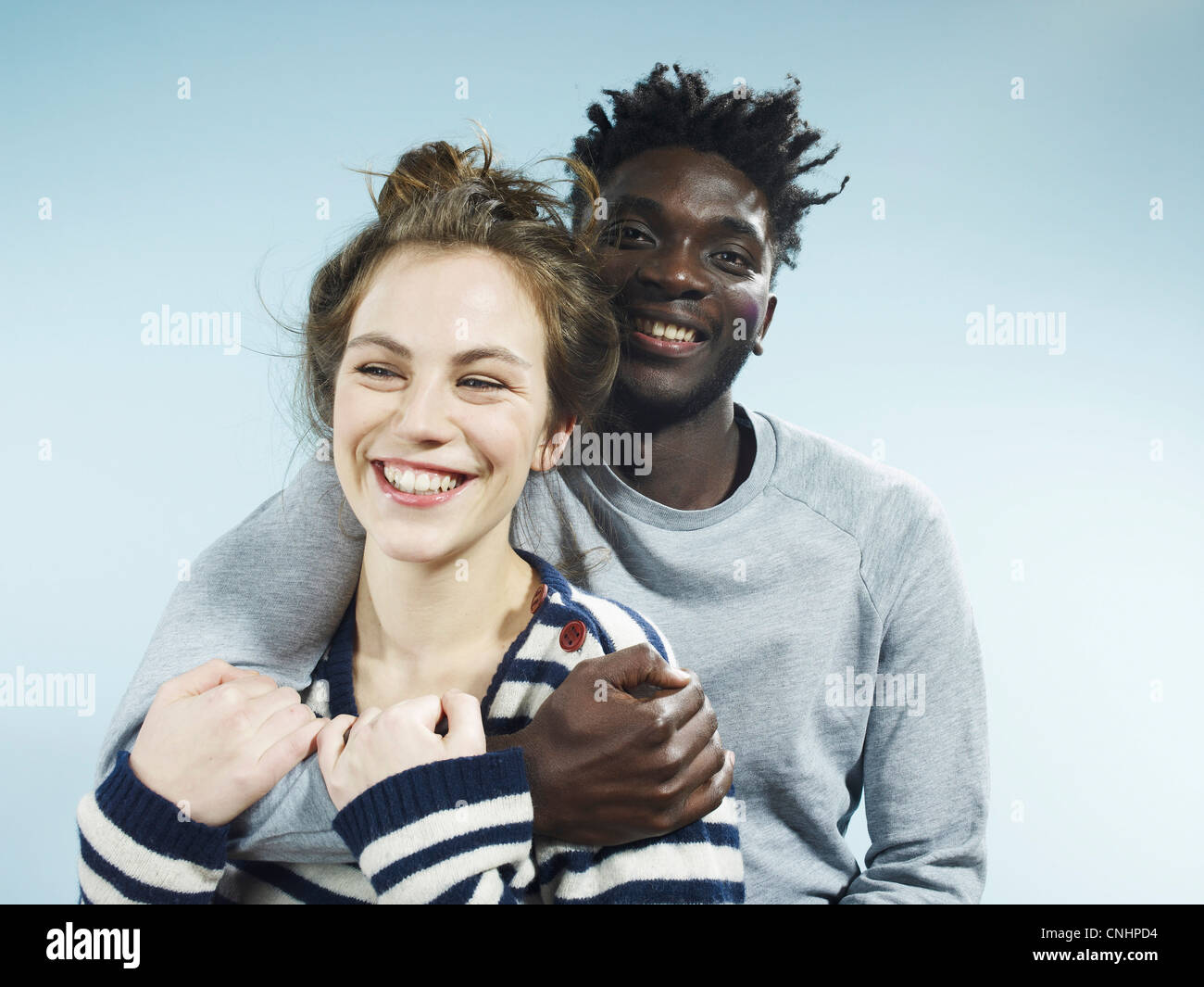 Ein lächelnder junge Mann umarmt seine lächelnde Freundin von hinten Stockfoto