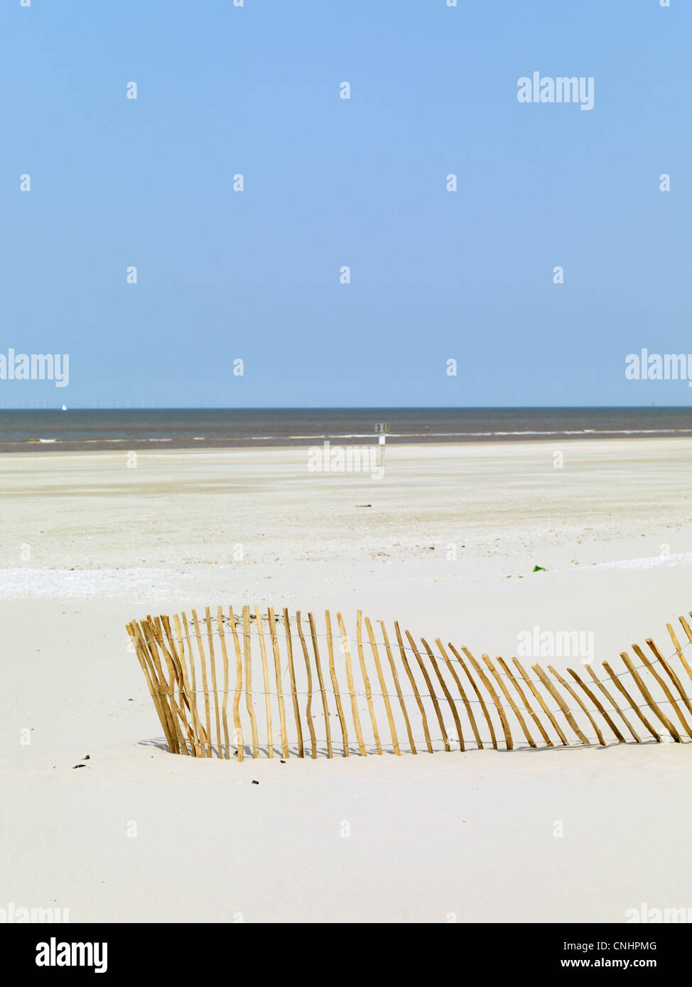 Ein schräg gestellter Zaun auf den Strand und das Meer im Hintergrund Stockfoto
