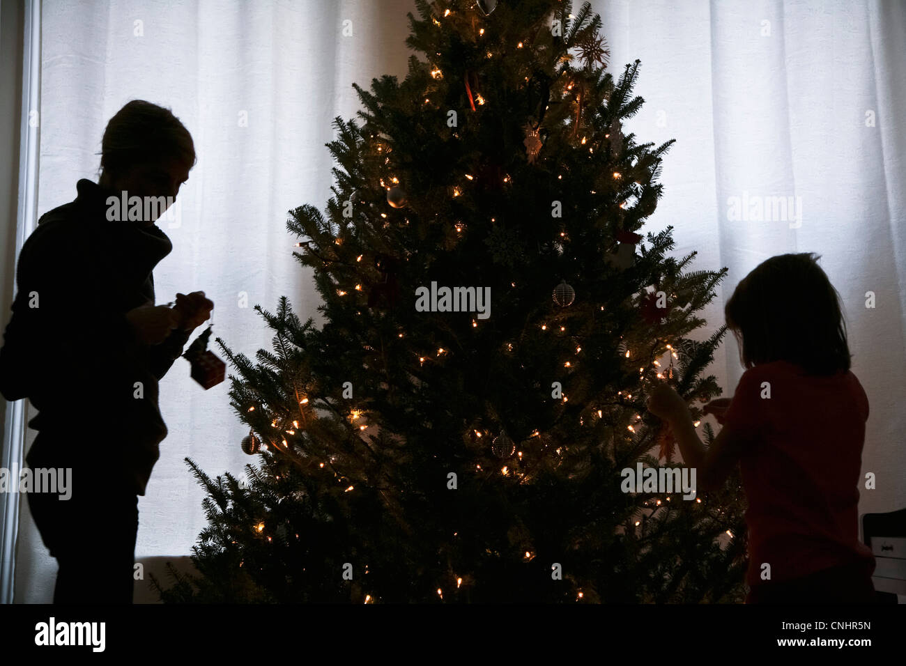 Silhouette von Mutter und Tochter einen Weihnachtsbaum zu verzieren Stockfoto