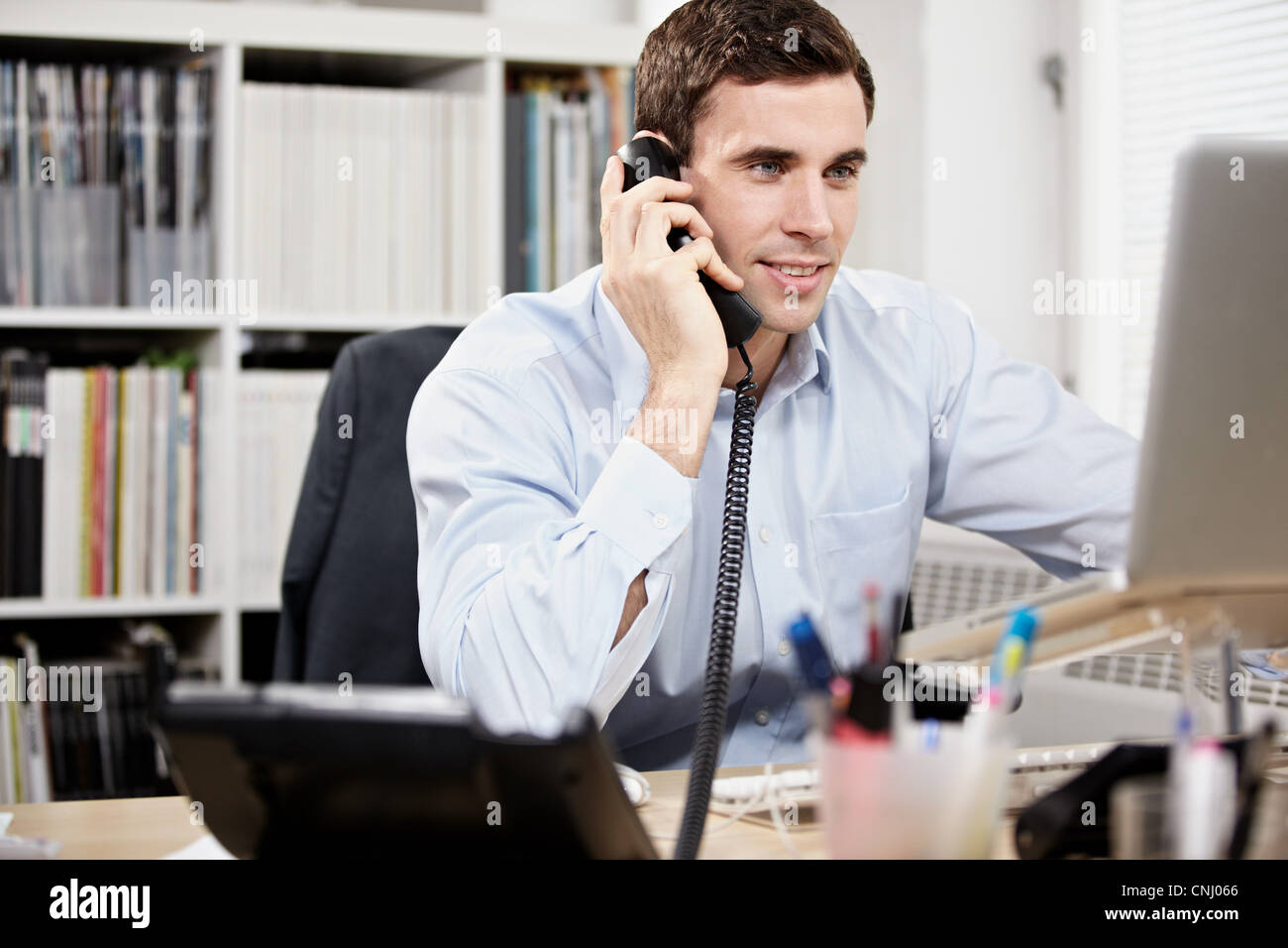 Junger Mann am Telefon und am laptop Stockfoto