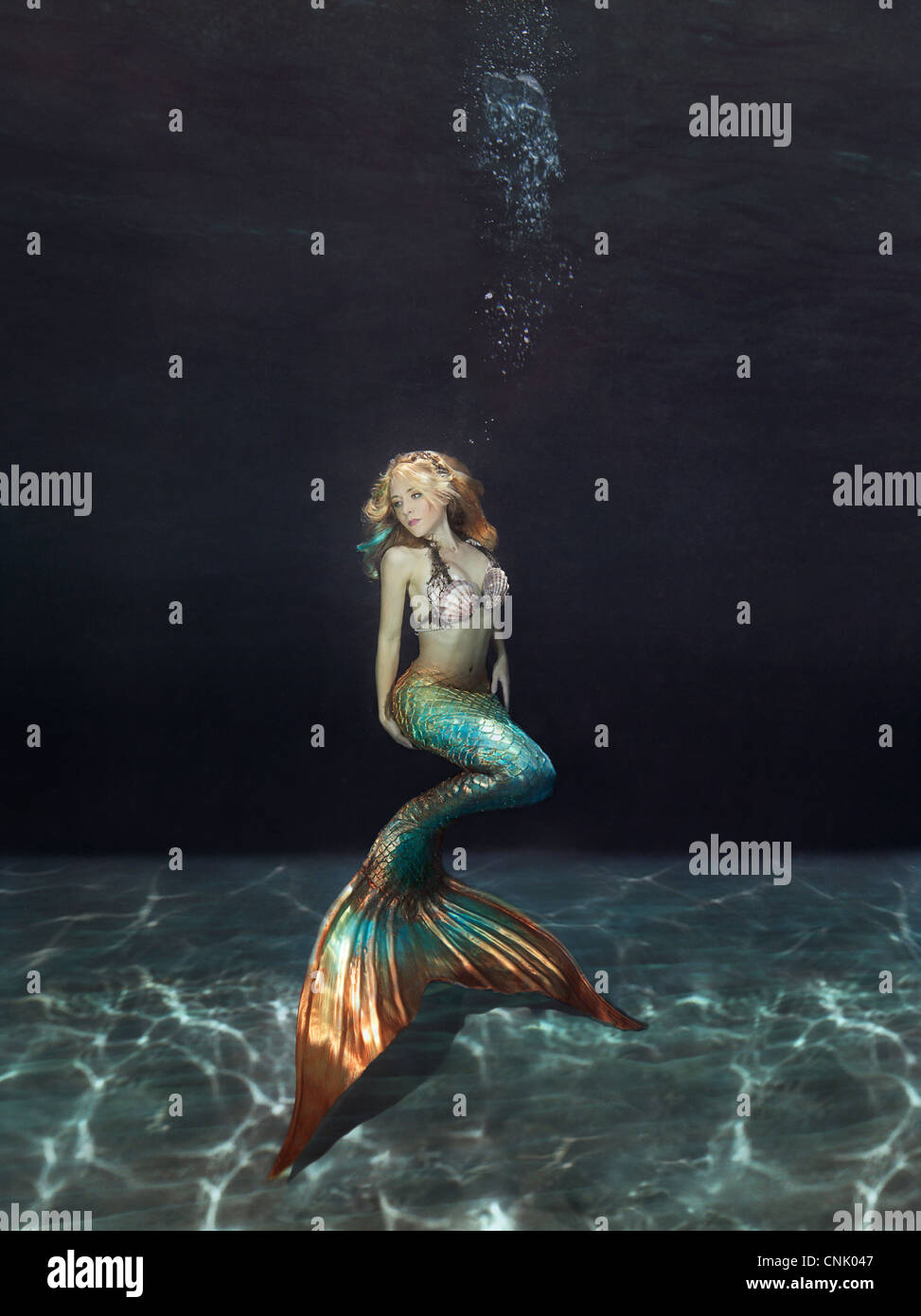 Mermaid Unterwasser schwebt über dem sandigen Boden Stockfoto