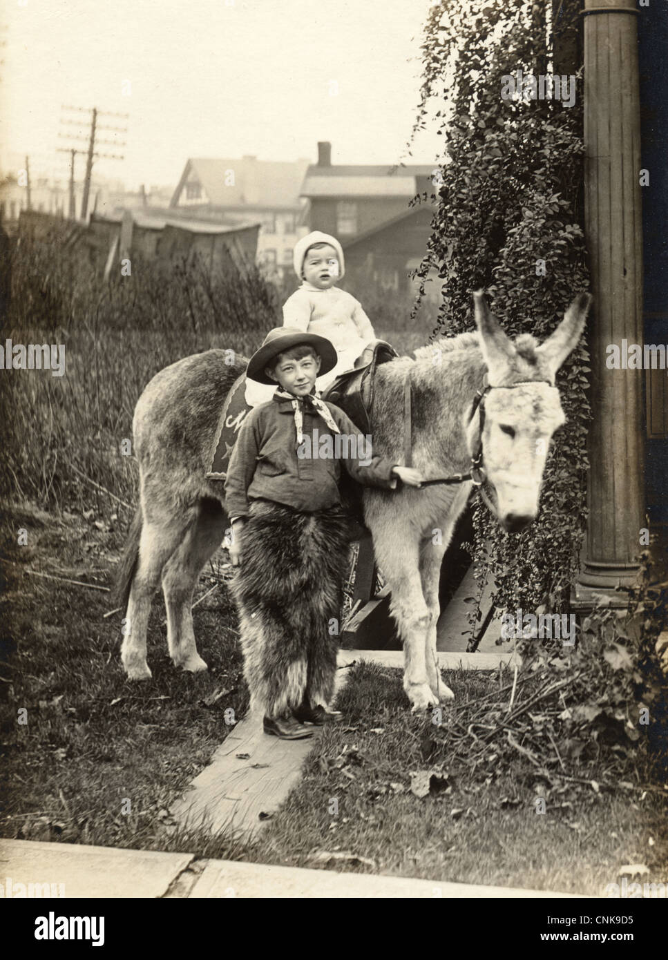Kleiner Cowboy mit Kleinkind Geschwister auf einem Esel Stockfoto