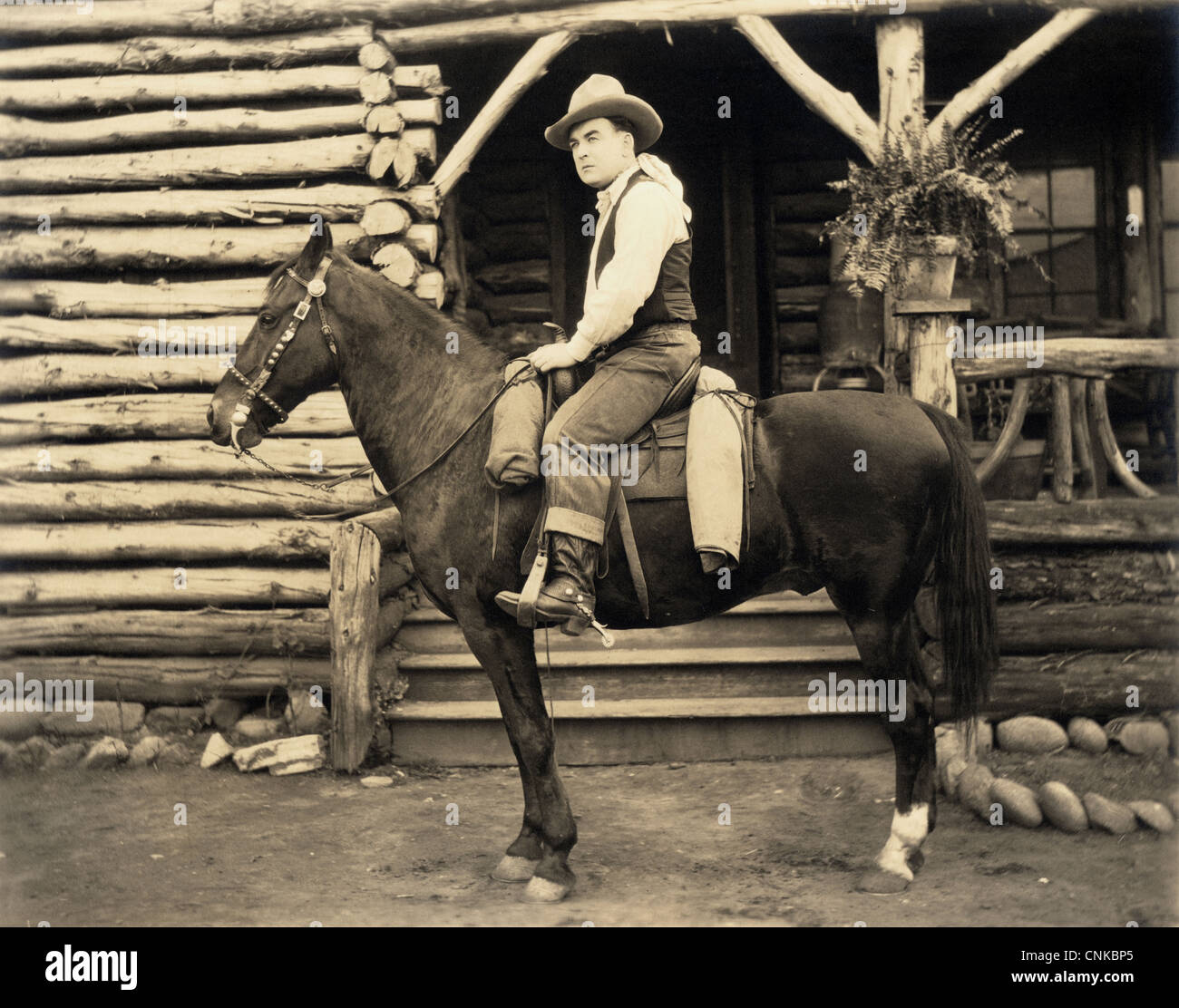 Cowboy zu Pferd in Blockhütte Stockfoto