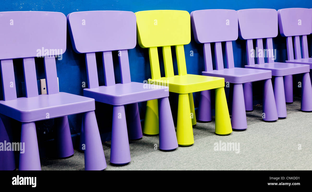 Eine gelb gefärbt in der Mitte mehrere lila farbigen Stühle für Kinder Stockfoto