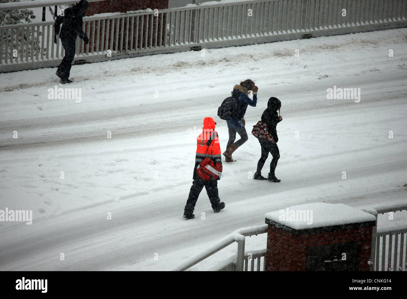Royal Mail Postbote und junge Menschen zu Fuß auf der Straße durch einen Schneesturm Stockfoto