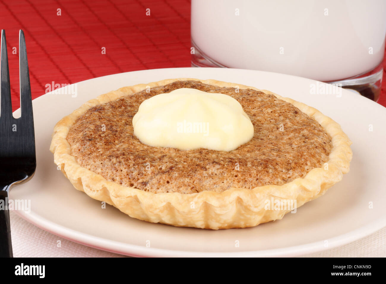 Walnuss Mini Törtchen mit Mascarpone Dessertgabel und ein Glas Milch auf einem roten Hintergrund Stockfoto