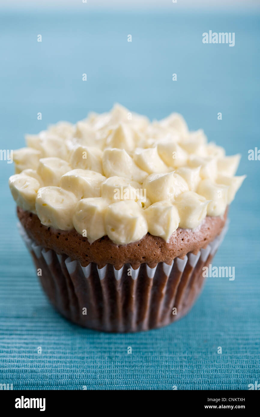 Lecker aussehende Schokolade Cupcake mit Vanille Zuckerguss auf Petrol grün Tischset-flacher Fokus Fotografie Stockfoto
