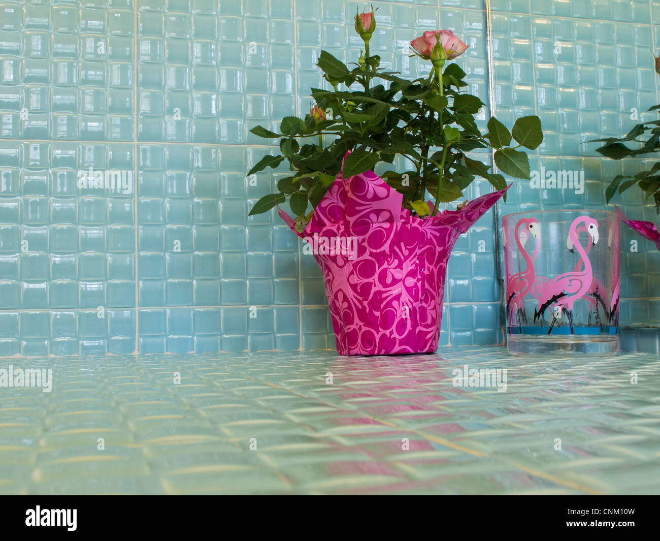 Retro-Florida Aqua geflieste Badezimmer mit Flamingo Kunststoffglas und Pflanze. Stockfoto