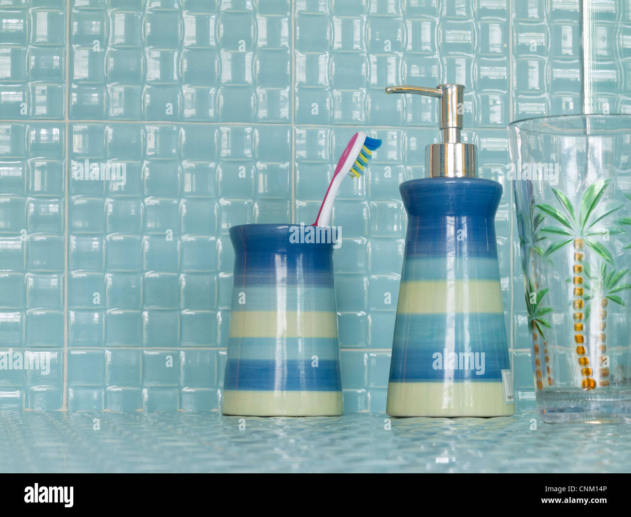 Passende Zahnbürste Cup und Seife Pumpe Behälter im Retro-Florida Aqua geflieste Badezimmer mit Kunststoff Palm Tree Glas. Stockfoto