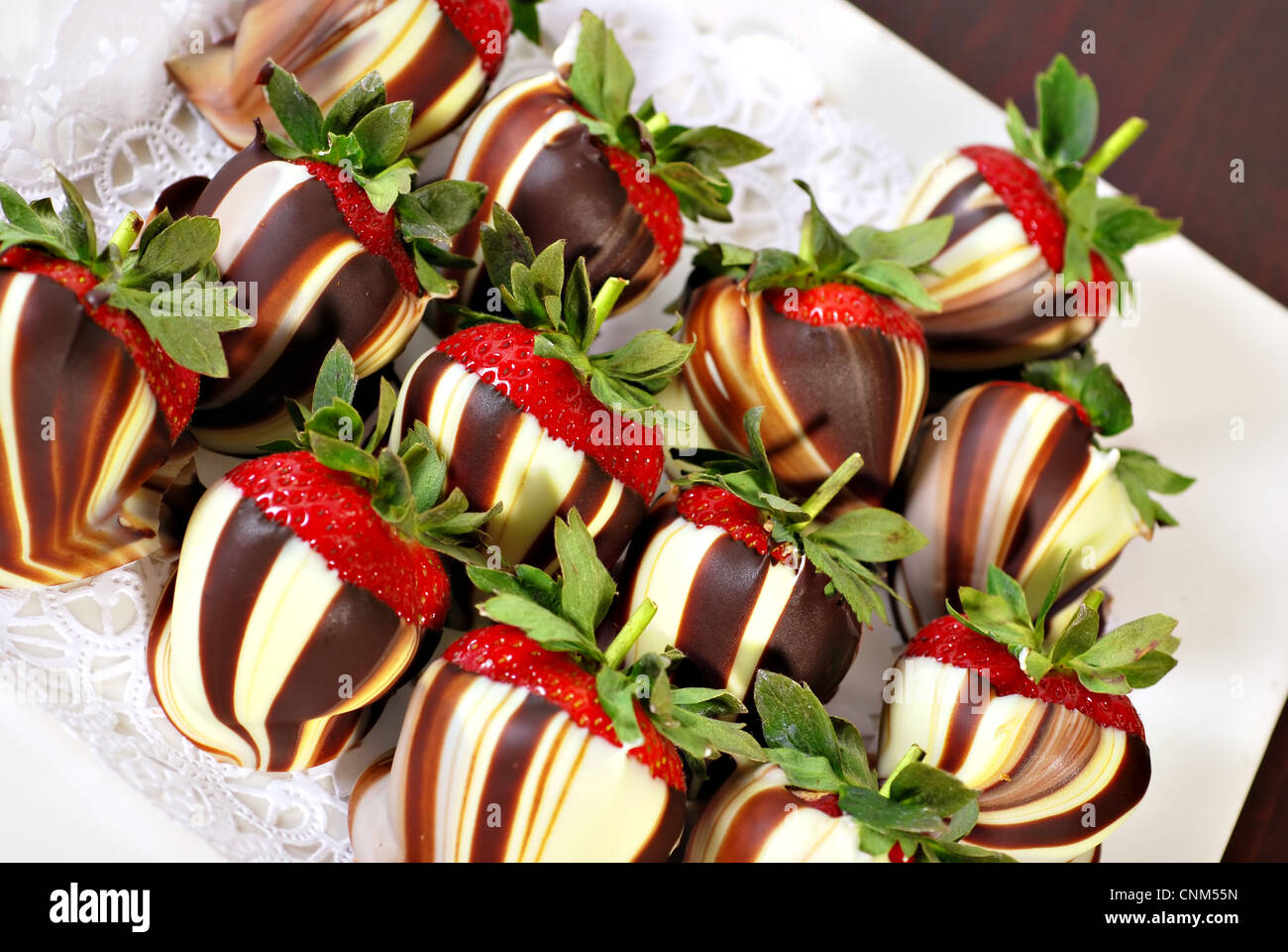 Weißer und brauner Schokolade überzogene Erdbeeren wirbelte auf Platte Stockfoto