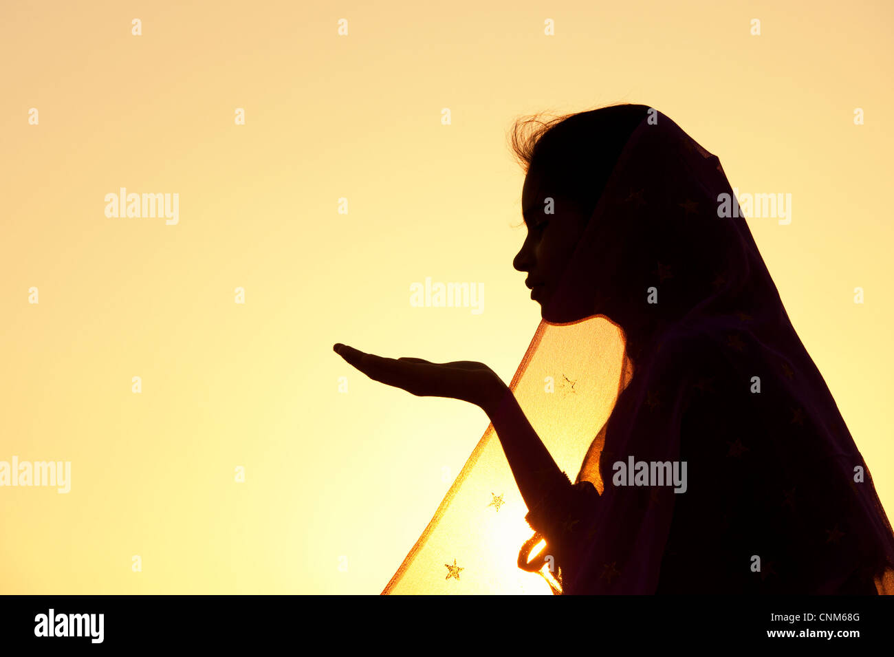 Indische Mädchen streckte ihre Hand tragen einen Sternen Schleier bei Sonnenuntergang. Silhouette. Indien Stockfoto