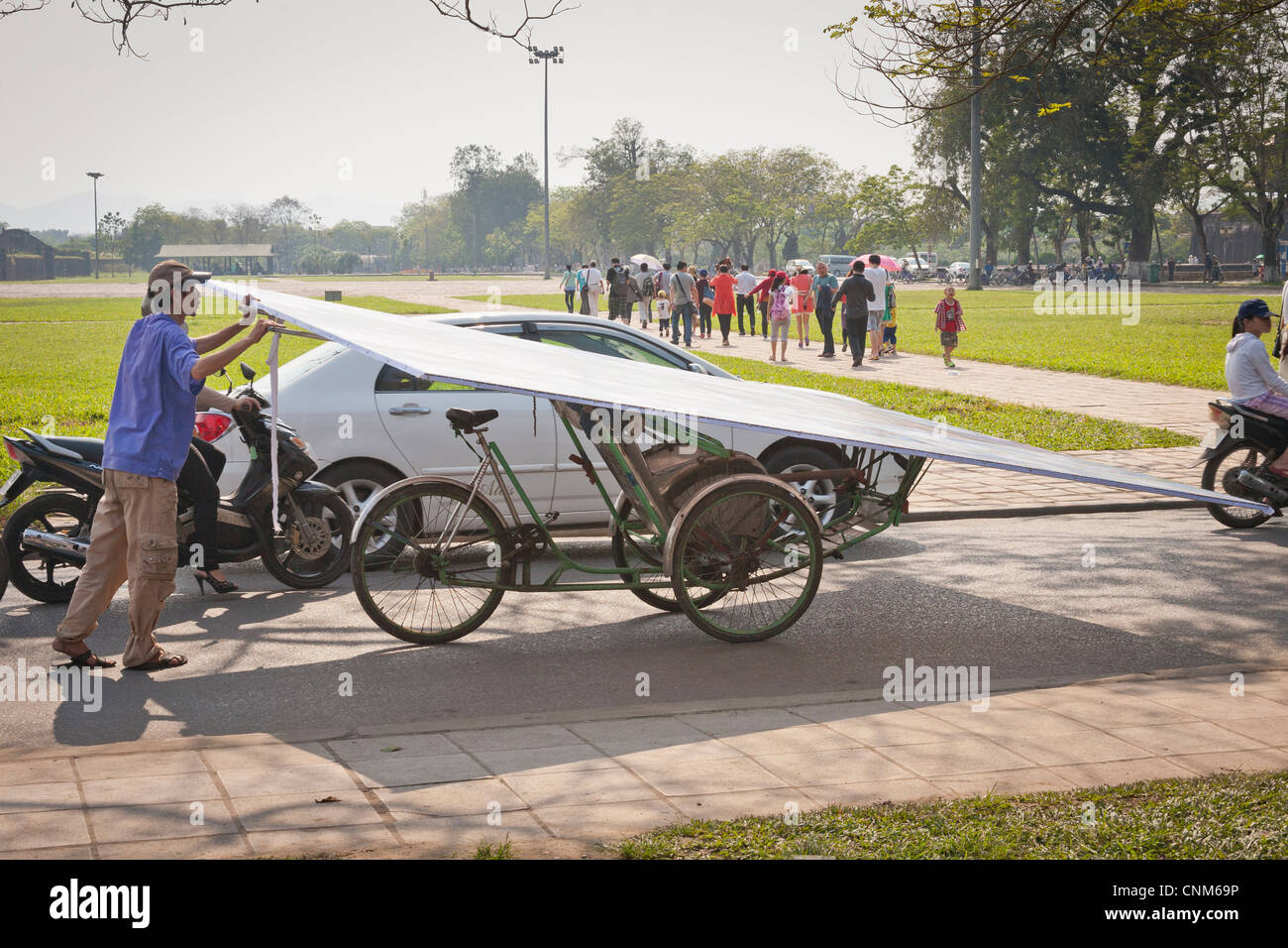 Mann, die Transport von großen Stück des Brettes auf seinem Dreirad, Hue, Vietnam Stockfoto