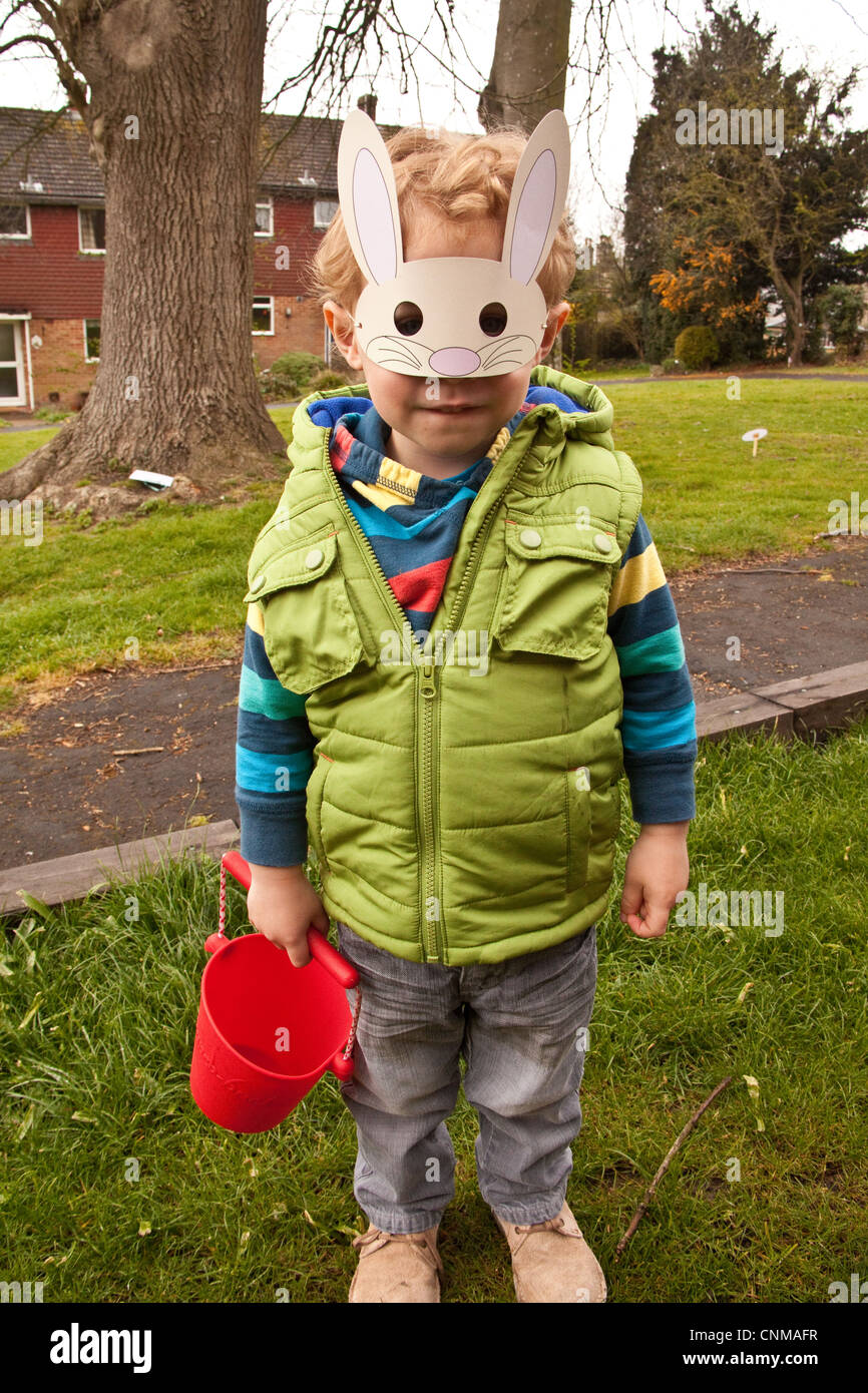 Drei Jahre alter Junge mit Ostern Hase Maske auf der Suche nach Ostereiern, Alresford, Hampshire, England. Stockfoto