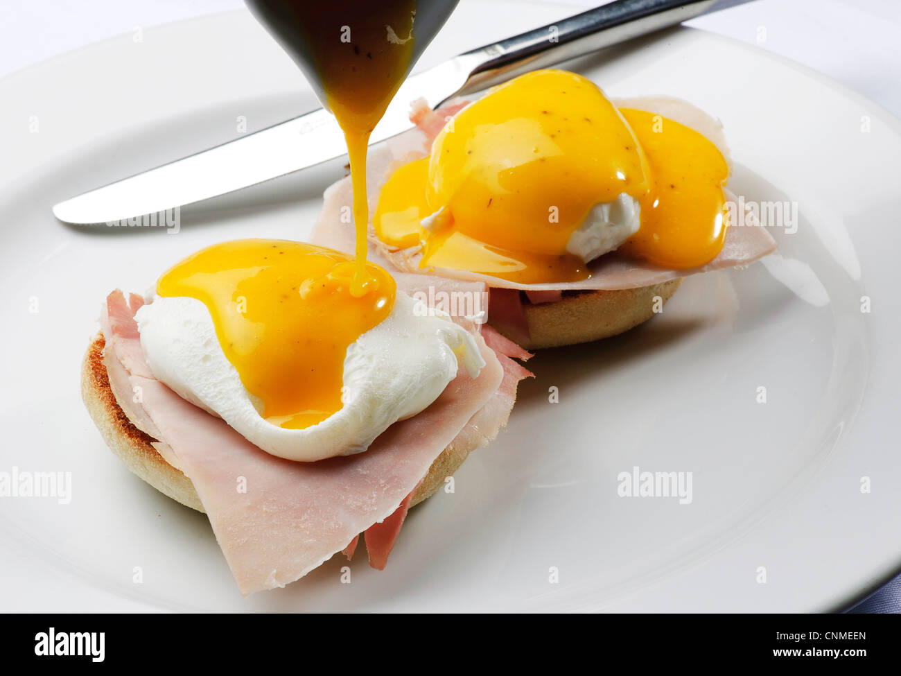 Teller mit Eiern Benedict zwei Hälften des englischen Muffin belegt mit Schinken oder Speck pochierten Eiern und Sauce Hollandaise Frühstücksbrunch Stockfoto